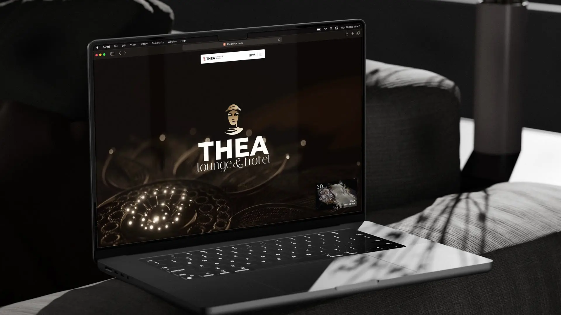 The Thea homepage on a laptop on a dark sofa: the name over the filigree film, a cream sheet sliding over it with Five rooms above the old town square, then the bar opening in an arch