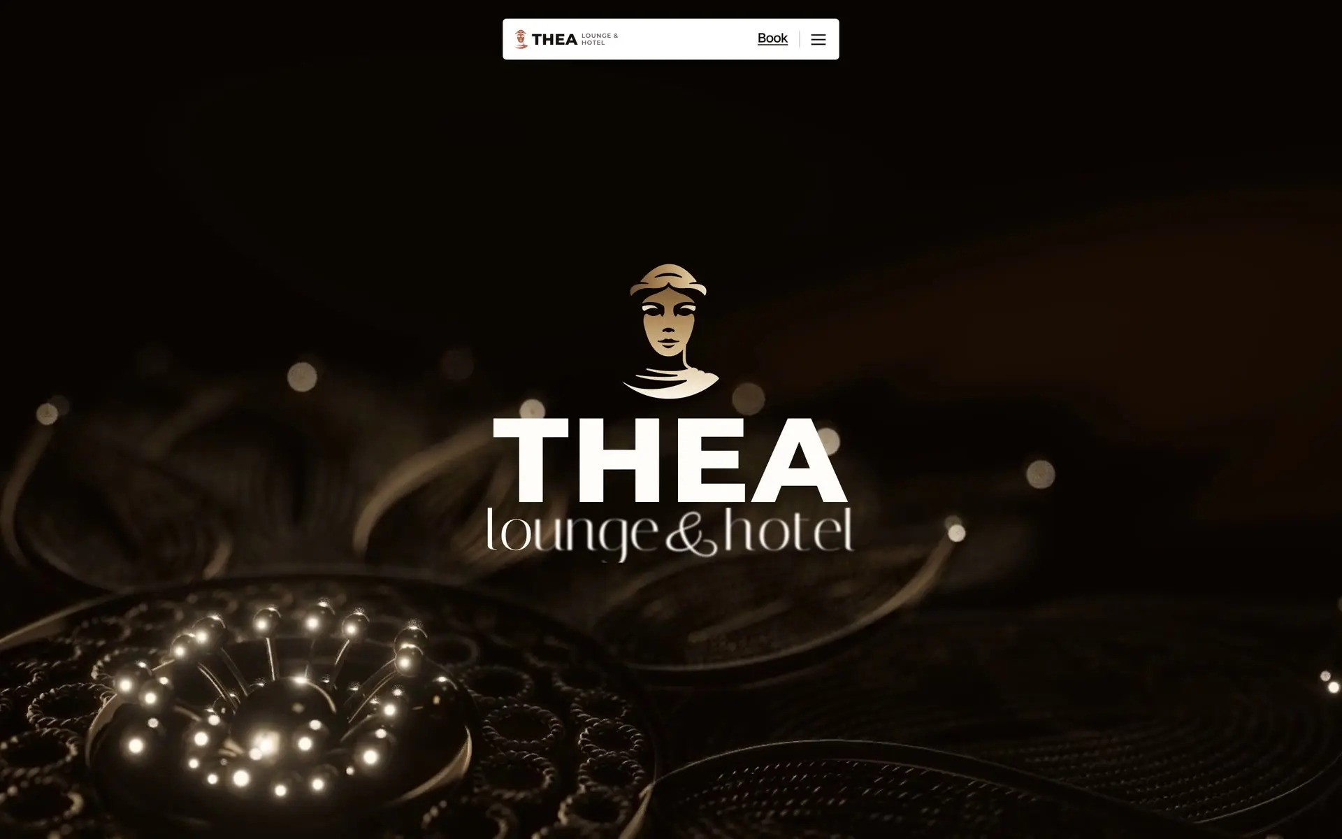 The Thea homepage: the hotel's goddess mark fills with light on a dark screen, then the words THEA lounge & hotel settle over a turning rosette of silver filigree in warm lamplight